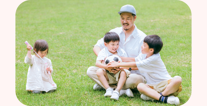 芝生の上で預かった子と遊んでいる男性の写真